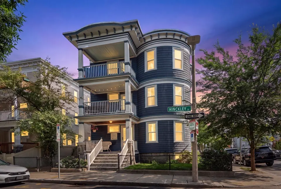 Victorian three-family home at dusk with blue siding, turret bay and stacked porches