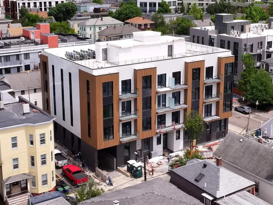 Finished multifamily facade with new panel siding and black-framed windows